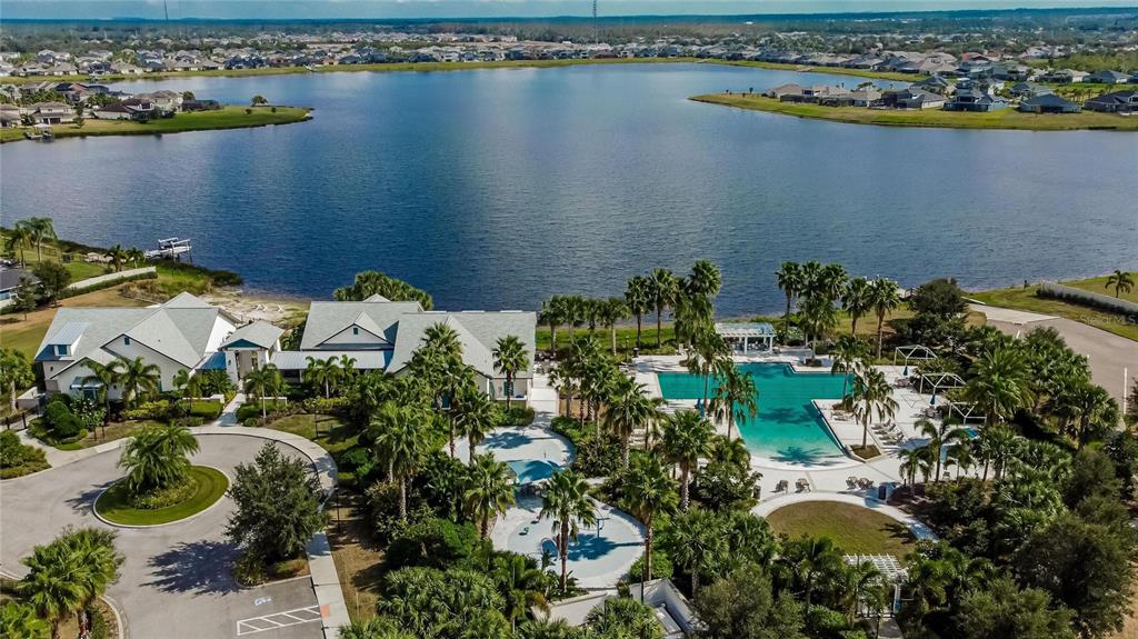 An aerial view shows a community swimming pool complex with a splash pad and clubhouse — 11628 LAKE LUCAYA DRIVE, RIVERVIEW, FL