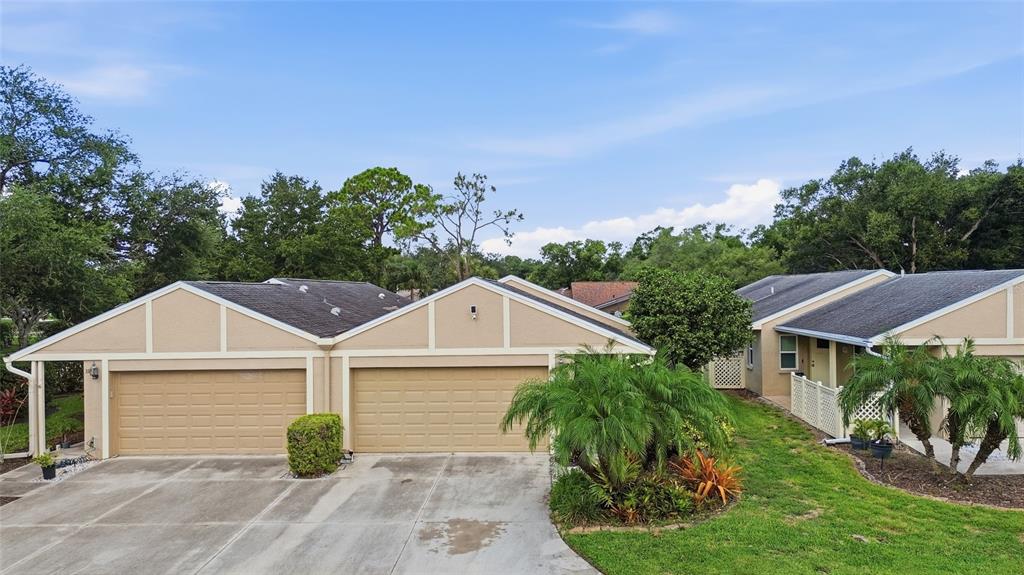 An exterior view of two attached single-story homes with tan stucco walls and garage doors — 308 CHARTLEY COURT N, SARASOTA, FL