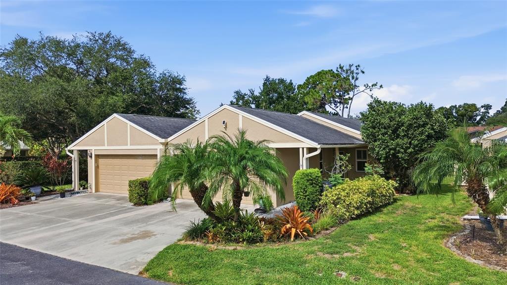 A single-story house with a tan exterior, a two-car garage, and a landscaped front yard — 308 CHARTLEY COURT N, SARASOTA, FL