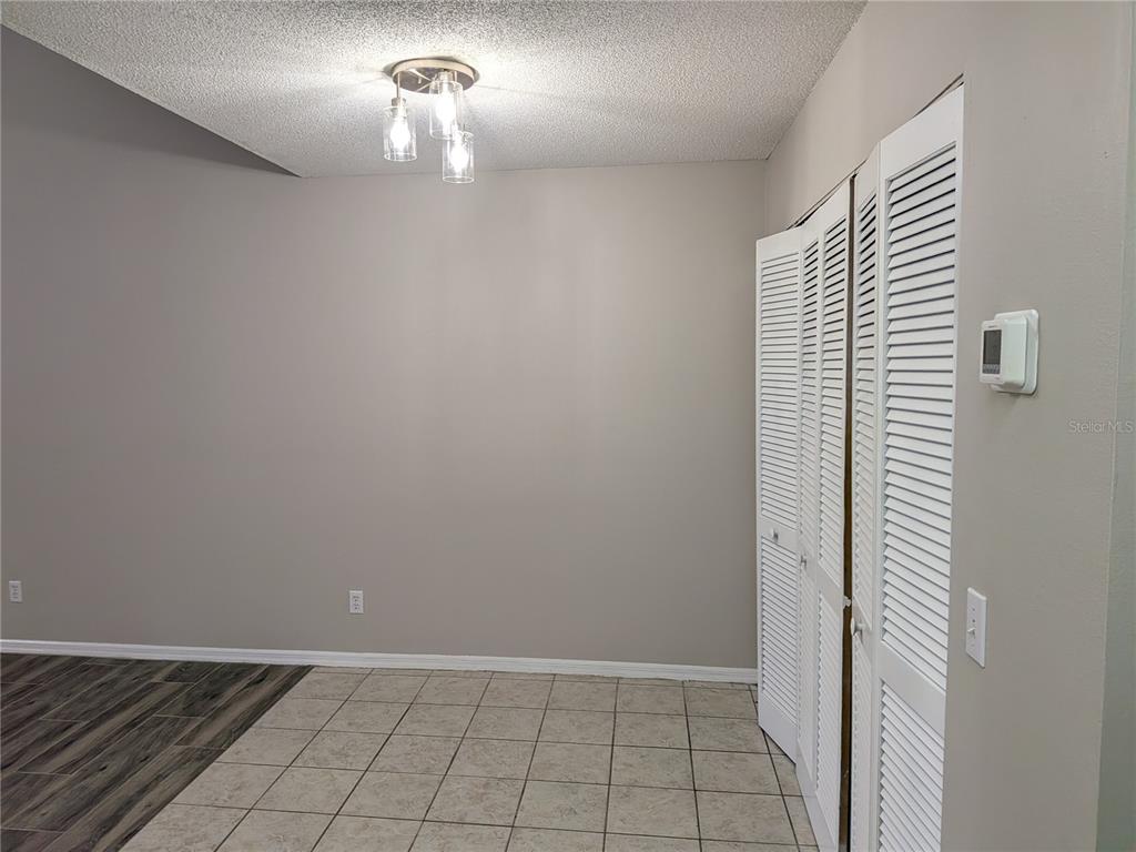 A room with tile flooring, a light fixture, and white louvered closet doors — 1020 HOWELL UNIT A7, BROOKSVILLE, FL