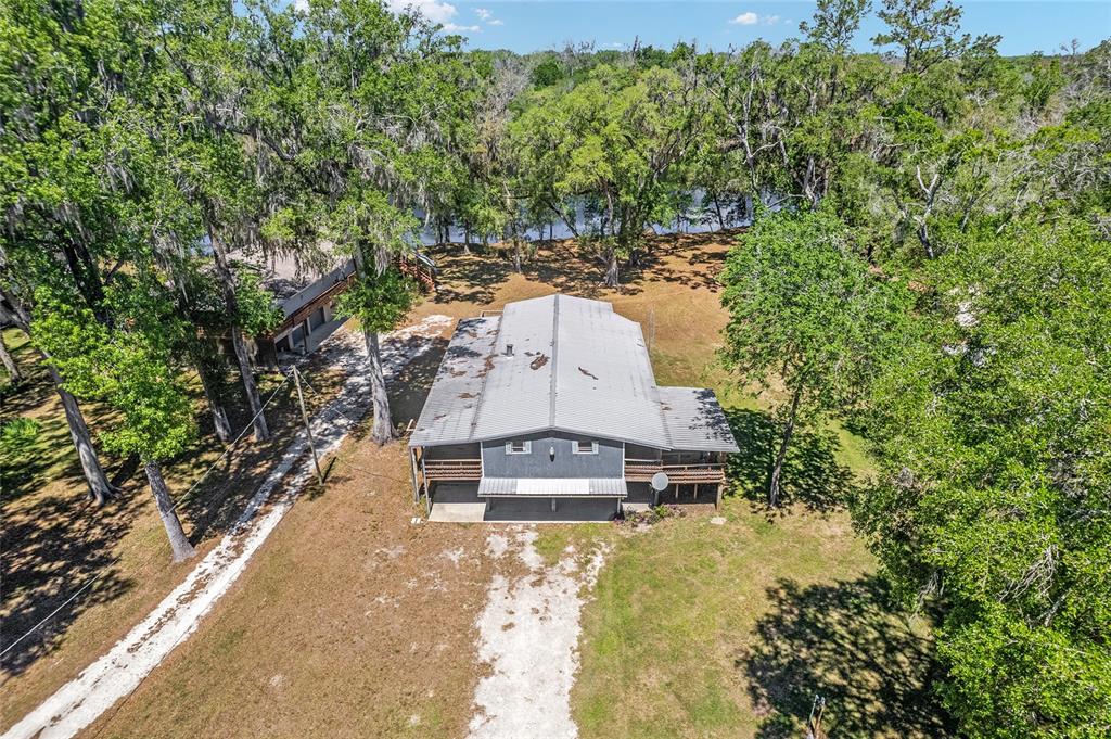 An aerial view shows a two-story house with a metal roof near a river — 7870 SW 25TH PLACE, BELL, FL