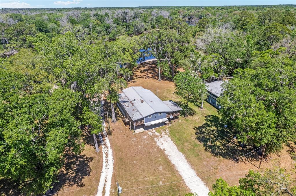 An aerial view shows a house with a metal roof situated on a wooded lot — 7870 SW 25TH PLACE, BELL, FL