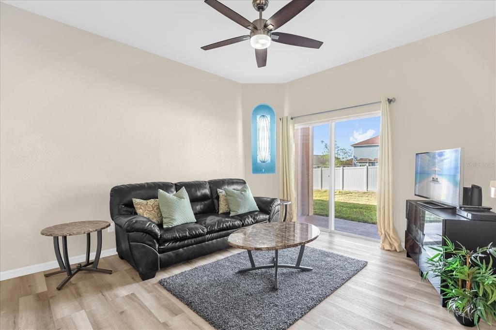 A living room features a black leather sofa, marble-topped tables, and sliding glass doors — 1144 CALABRIA AVENUE, DAVENPORT, FL