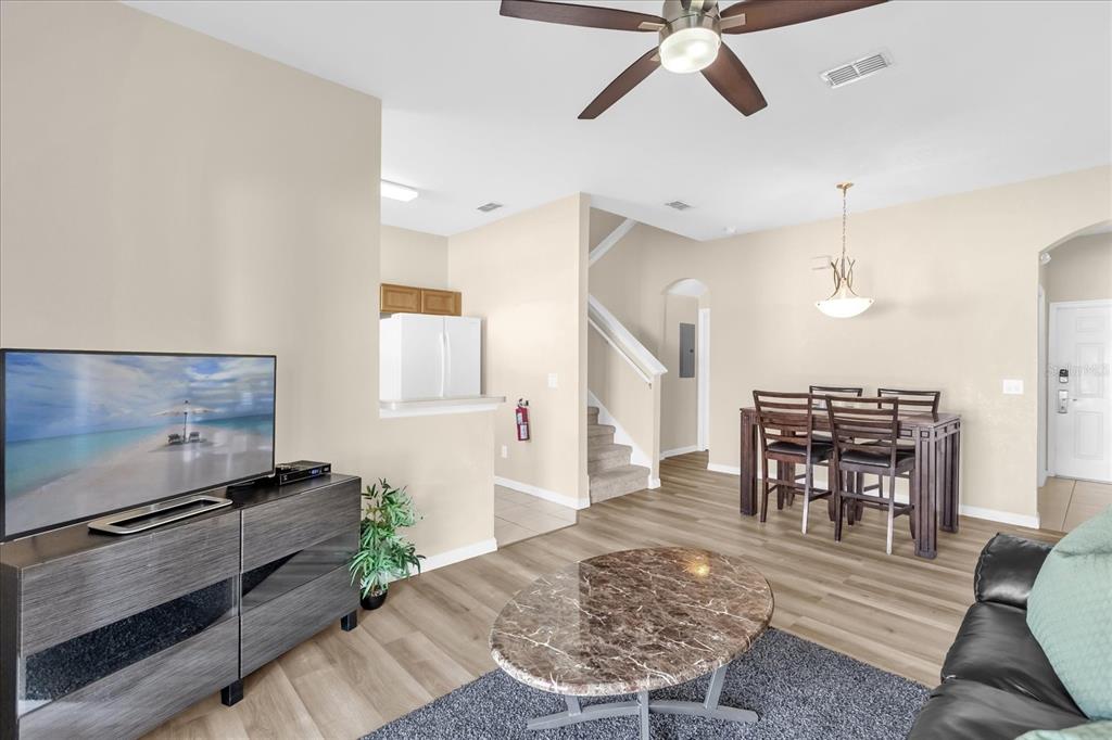 A living room and dining area with wood-look flooring, a ceiling fan, and stairs — 1144 CALABRIA AVENUE, DAVENPORT, FL