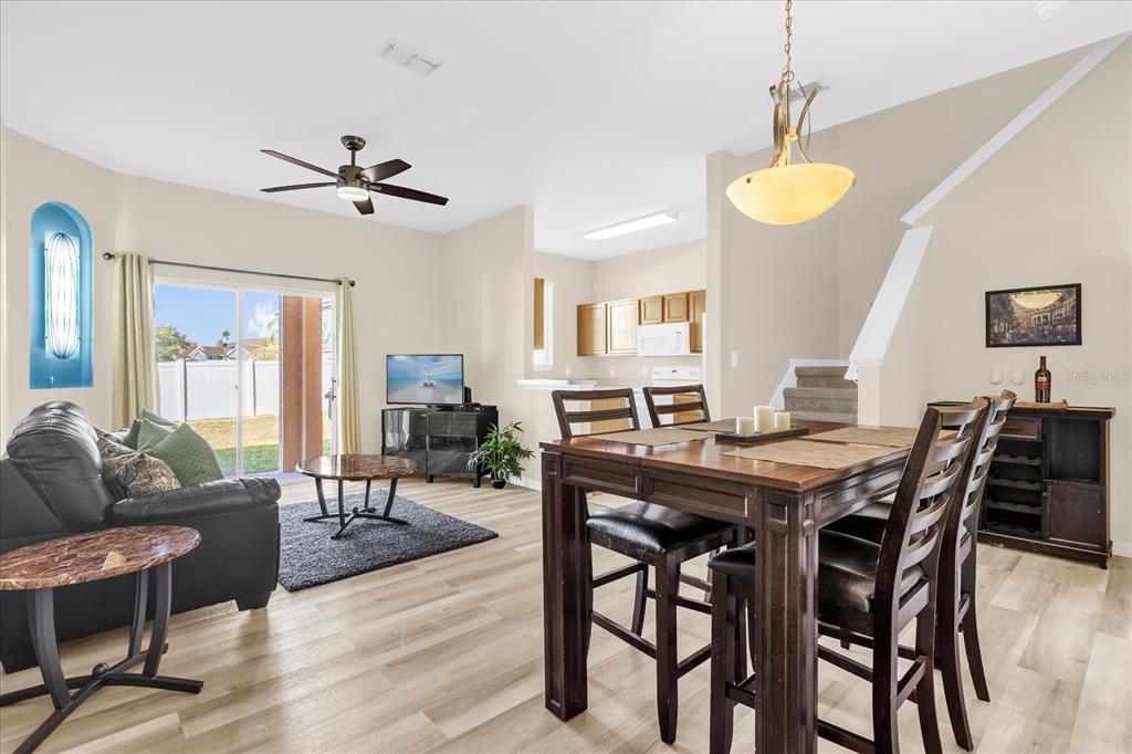 A living and dining area with wood-look flooring, a ceiling fan, and sliding glass doors — 1144 CALABRIA AVENUE, DAVENPORT, FL
