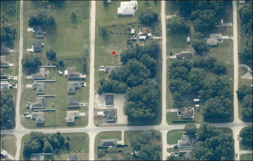 This aerial view shows a residential lot marked with a red pin among trees — Lot 5 SW 113 PLACE, DUNNELLON, FL
