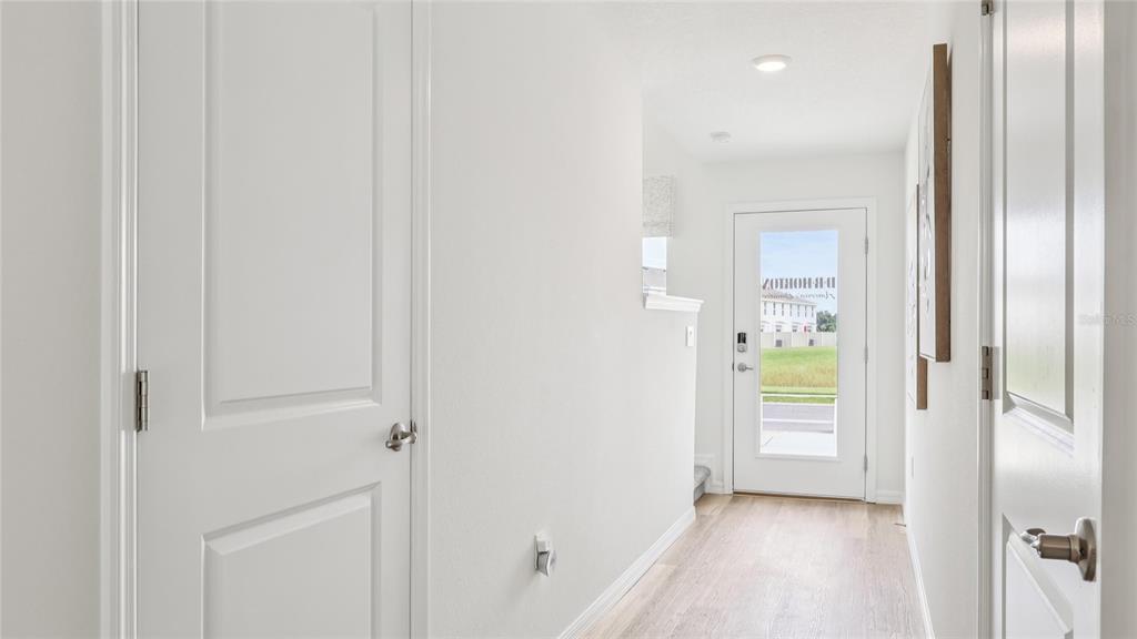 A bright entryway features light wood-look flooring, white walls, and a glass-paneled front door — 8308 GOWER TRAIL, WILDWOOD, FL