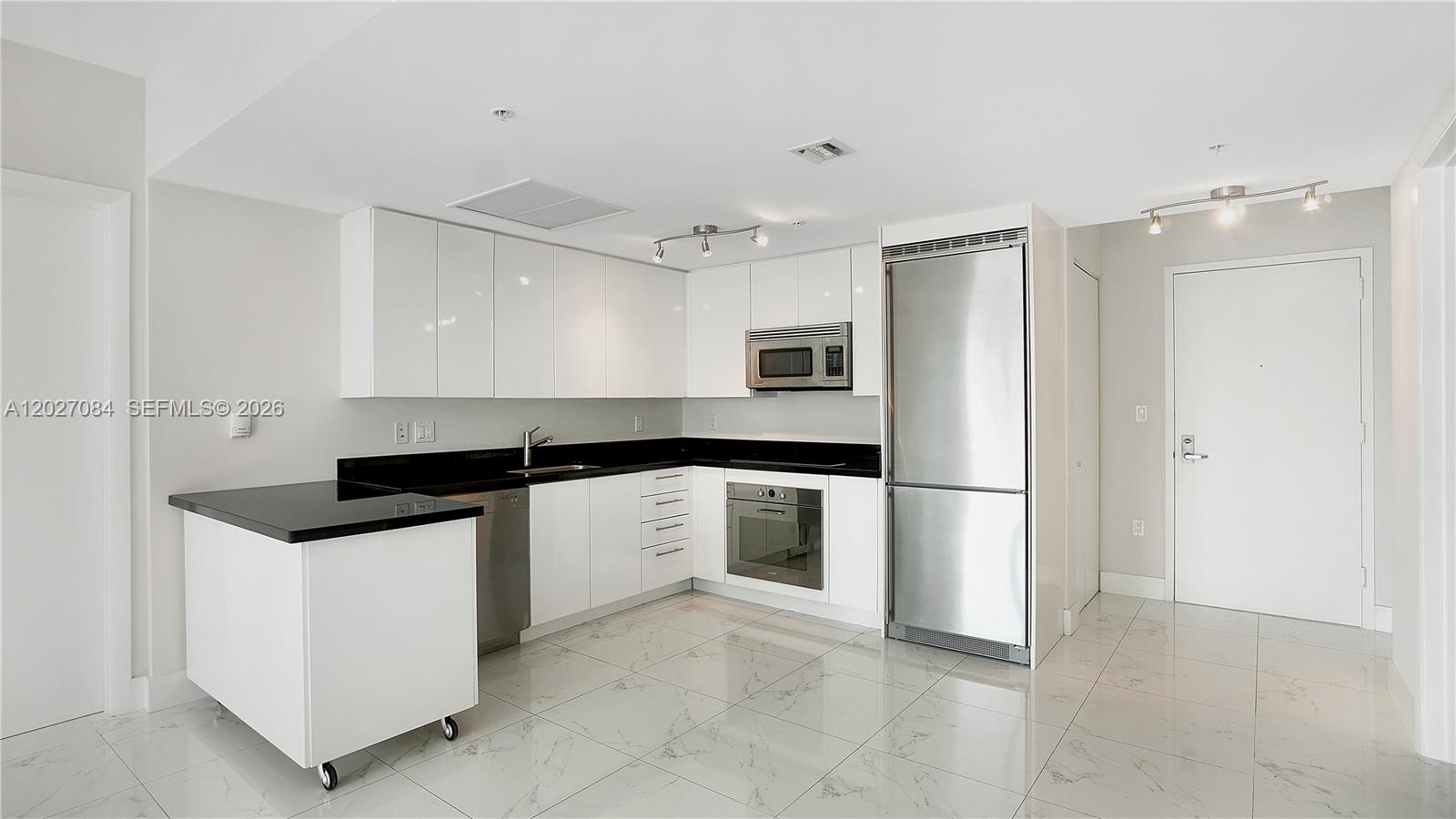 A modern kitchen features white cabinets, black countertops, stainless steel appliances, and marble-patterned tile floors — 92 SW 3rd St # 1803, Miami FL 33130, MIAMI, FL