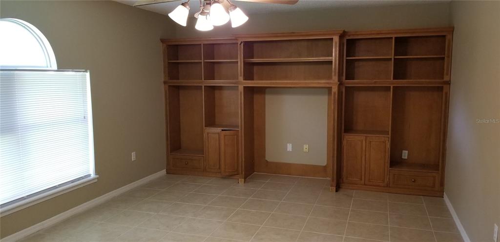 A room with tile flooring, a window with blinds, and a large built-in wooden wall unit — 4040 IVEYGLEN AVENUE, ORLANDO, FL