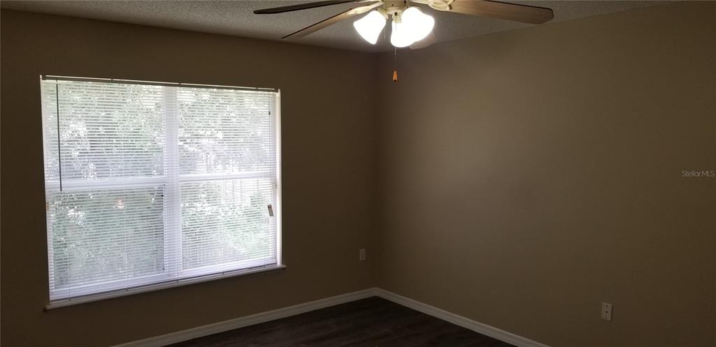 An empty bedroom features beige walls, a ceiling fan, and a window with white blinds — 4040 IVEYGLEN AVENUE, ORLANDO, FL