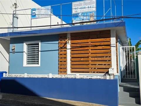 A blue building exterior features a window with security bars and a wooden slat privacy screen — 173 CALLE FLORIDA, LUQUILLO, PR