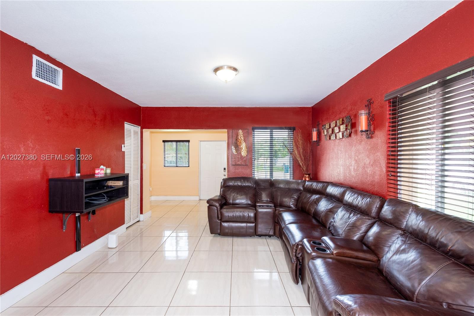 A living room features red walls, a brown leather sectional sofa, and light tile flooring — 12741 Wood St, Miami FL 33167, MIAMI, FL