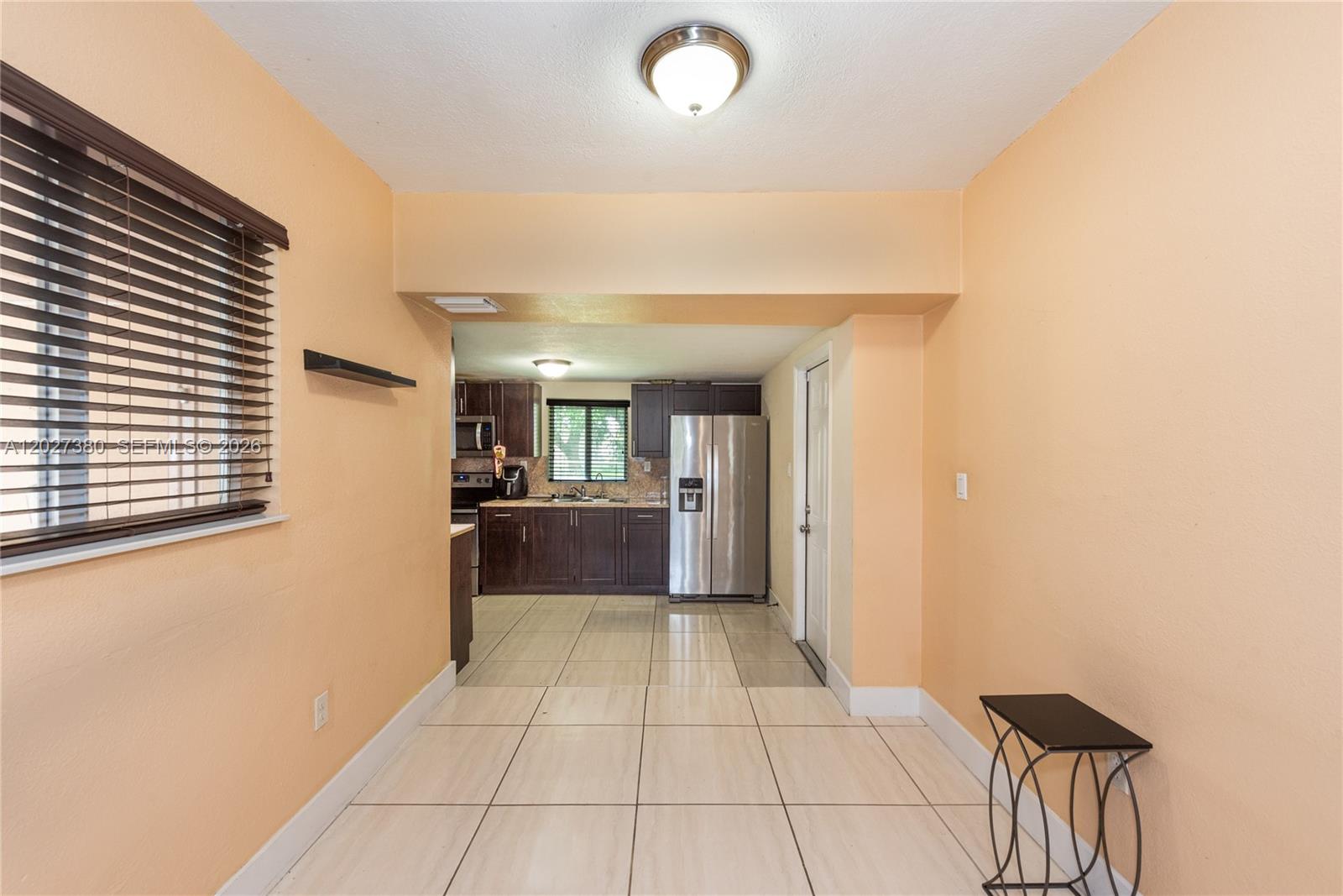 A dining area with tile floors leads into a kitchen featuring dark wood cabinets — 12741 Wood St, Miami FL 33167, MIAMI, FL