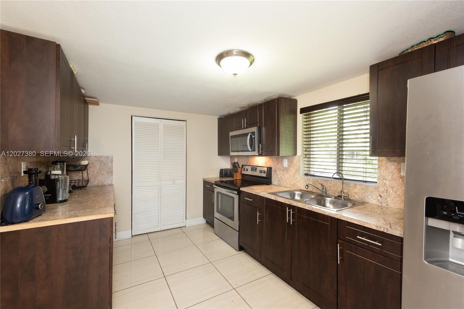 A kitchen features dark wood cabinets, stainless steel appliances, and light-colored tile flooring — 12741 Wood St, Miami FL 33167, MIAMI, FL