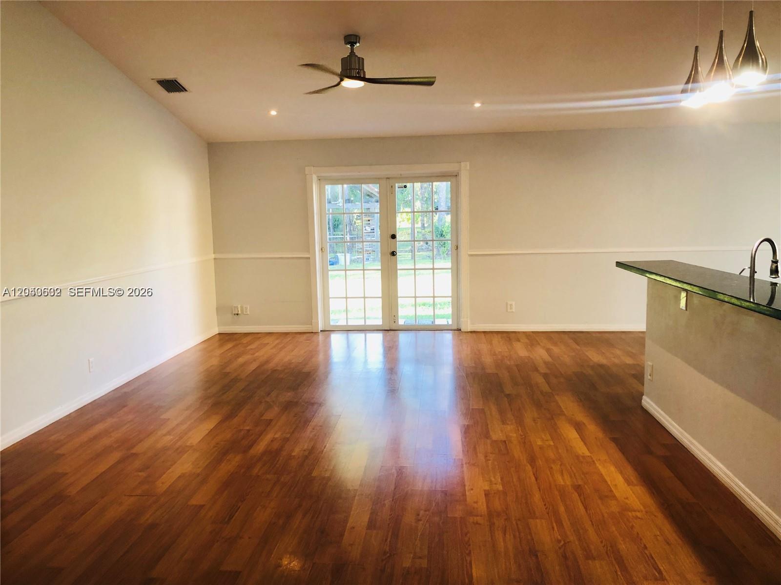 An open living area features hardwood floors, a ceiling fan, and glass double doors — 13677 Temple Blvd, West Palm Beach FL 33412, WEST PALM BEACH, FL