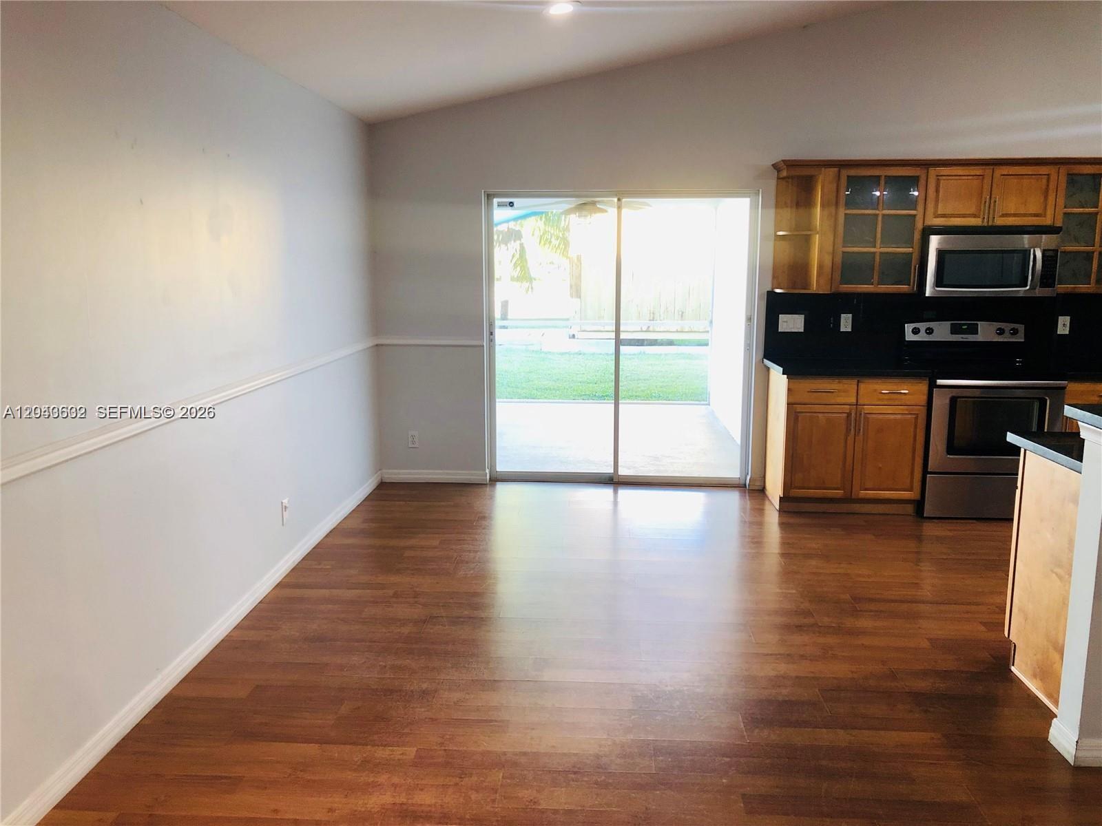 A dining area with wood-look flooring, chair rail molding, and an adjacent kitchen — 13677 Temple Blvd, West Palm Beach FL 33412, WEST PALM BEACH, FL