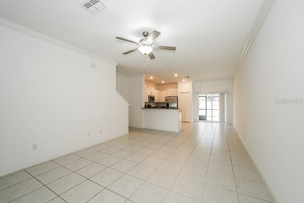 A living room with tile flooring leads to an open kitchen with white cabinets — 2182 AZURE VIEW WAY, LUTZ, FL