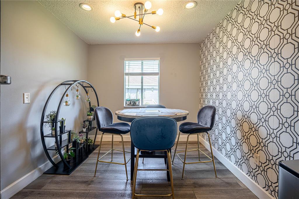 A dining area features a round table, three blue velvet chairs, and a geometric wallpaper accent — 3816 CORTEZ DRIVE UNIT D, TAMPA, FL