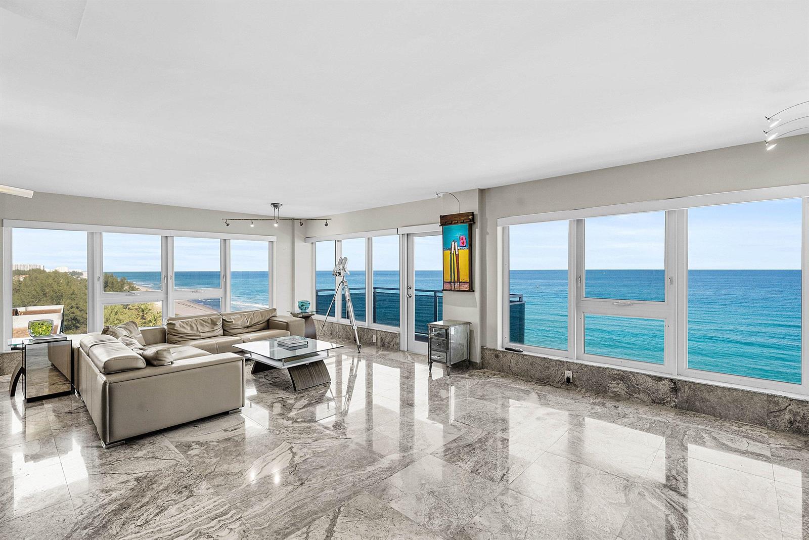 A living room with marble floors, a leather sectional, and floor-to-ceiling windows overlooking the ocean — 2066 N Ocean Boulevard, Boca Raton FL 33431, BOCA RATON, FL