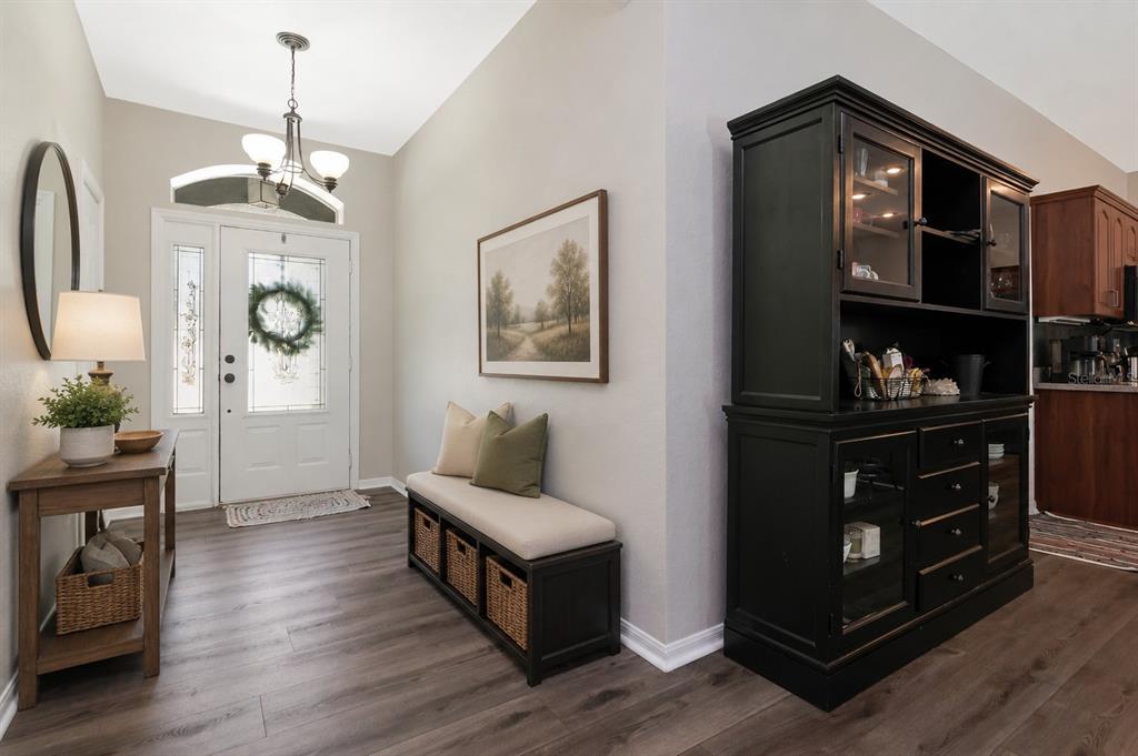 An entryway features wood-look flooring, a bench with storage baskets, and a large black hutch — 219 WILLOW BEND PARKWAY, LUTZ, FL