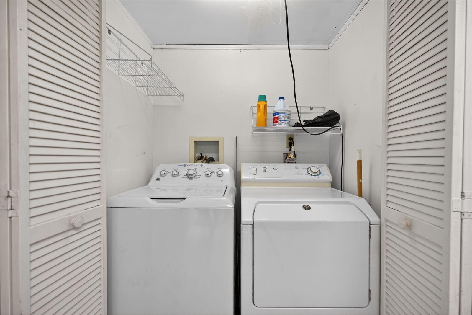 A laundry closet contains a white top-loading washing machine and a dryer with wire shelving — 707 Stonewood Court # 19c, Jupiter FL 33458, JUPITER, FL