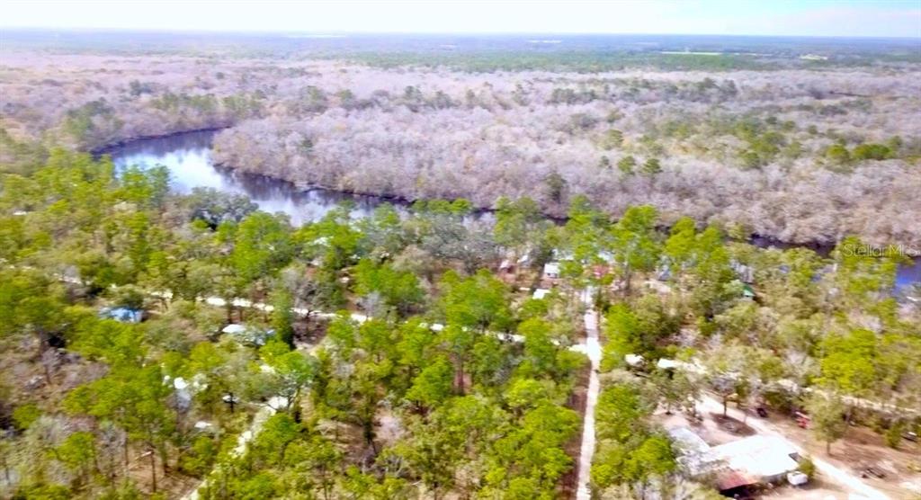 An aerial view shows a river winding through a dense, wooded landscape with scattered houses — 7809 SW 12TH PLACE, BELL, FL
