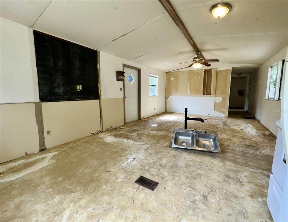 An unfinished room features exposed subflooring, a detached kitchen sink, and bare wall panels — 7809 SW 12TH PLACE, BELL, FL