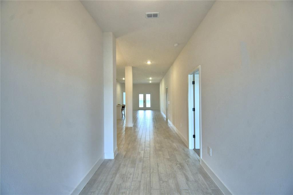 An interior view shows a tiled entryway leading into an open-concept living area and kitchen — 4616 CALAMINT LANE, AUBURNDALE, FL