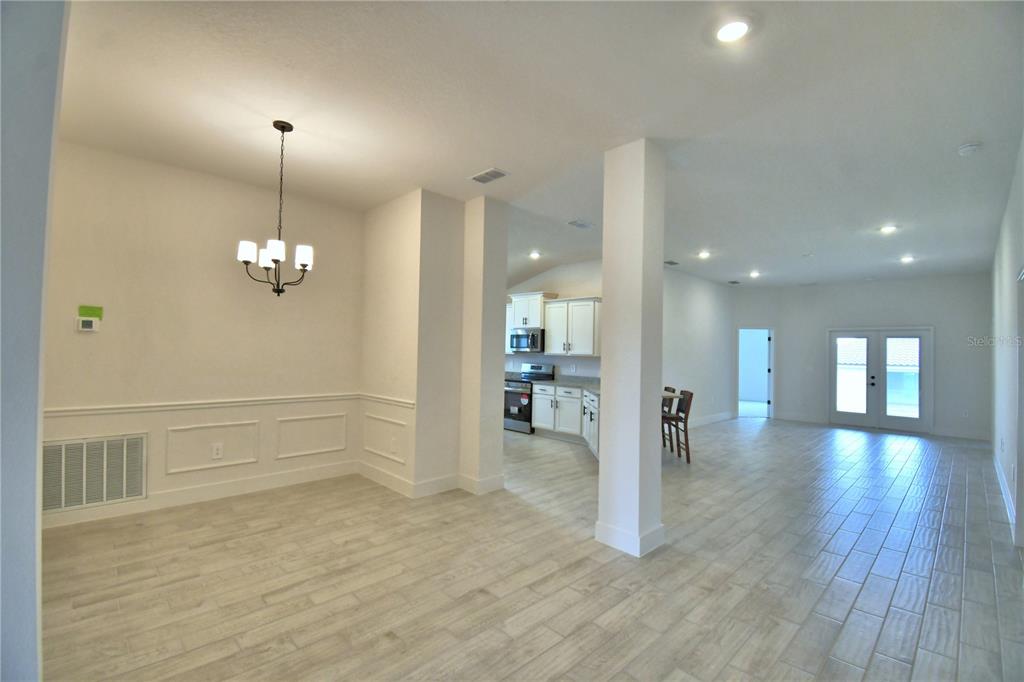 An open-concept dining area features tile flooring, a chandelier, and a view into the kitchen — 4616 CALAMINT LANE, AUBURNDALE, FL