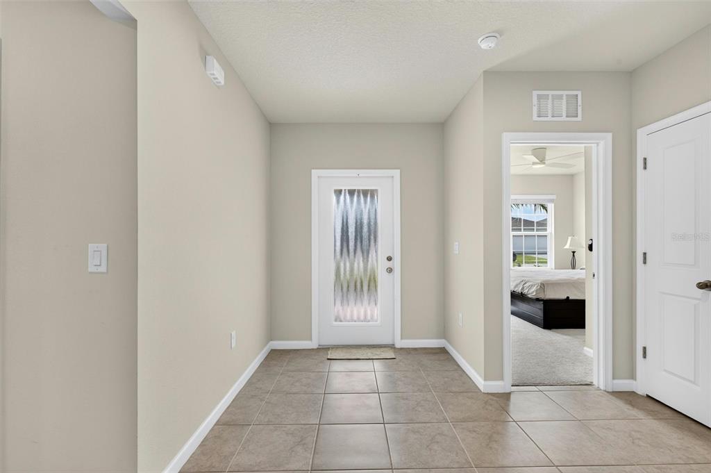A tiled entryway features a front door with a frosted glass insert and a bedroom — 153 EAGLE HARBOR WAY, DAYTONA BEACH, FL