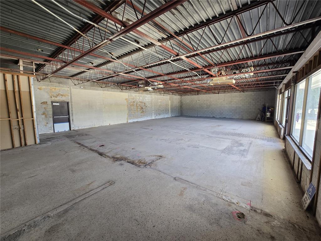 An unfinished commercial space features exposed steel trusses, concrete block walls, and a concrete floor — 8801 20TH STREET, VERO BEACH, FL