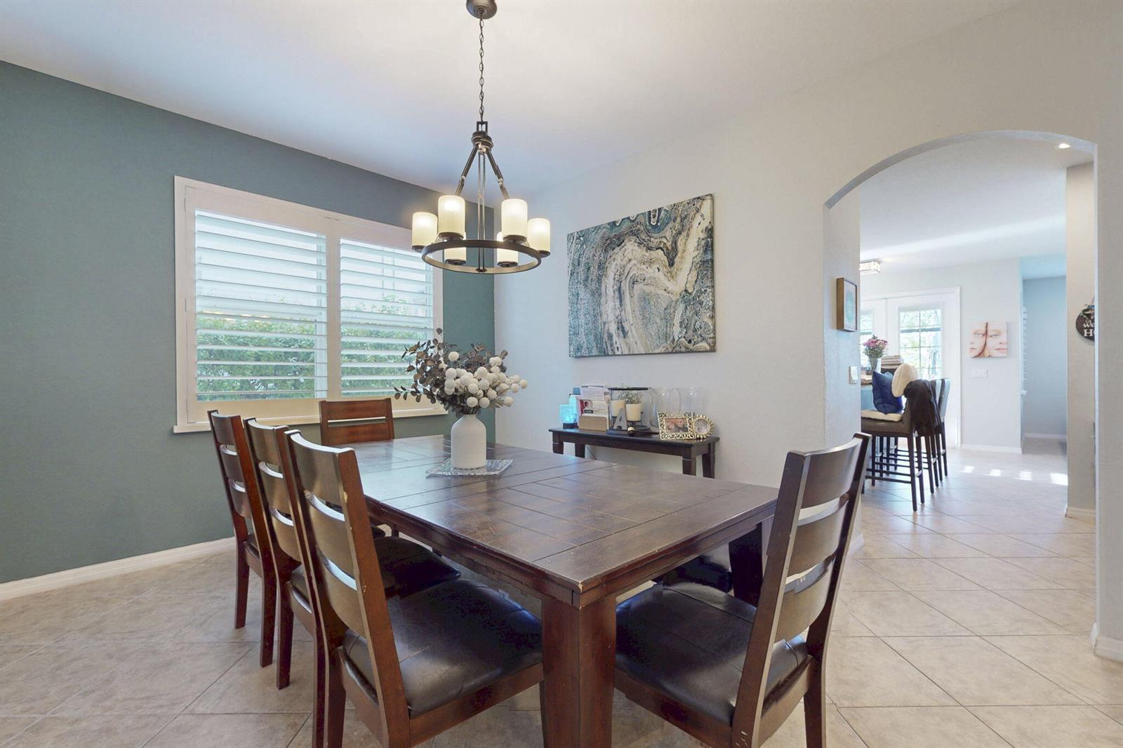 A dining room features a dark wood table, six chairs, a chandelier, and blue accent wall — 10551 Long Leaf Lane, Wellington FL 33414, WELLINGTON, FL