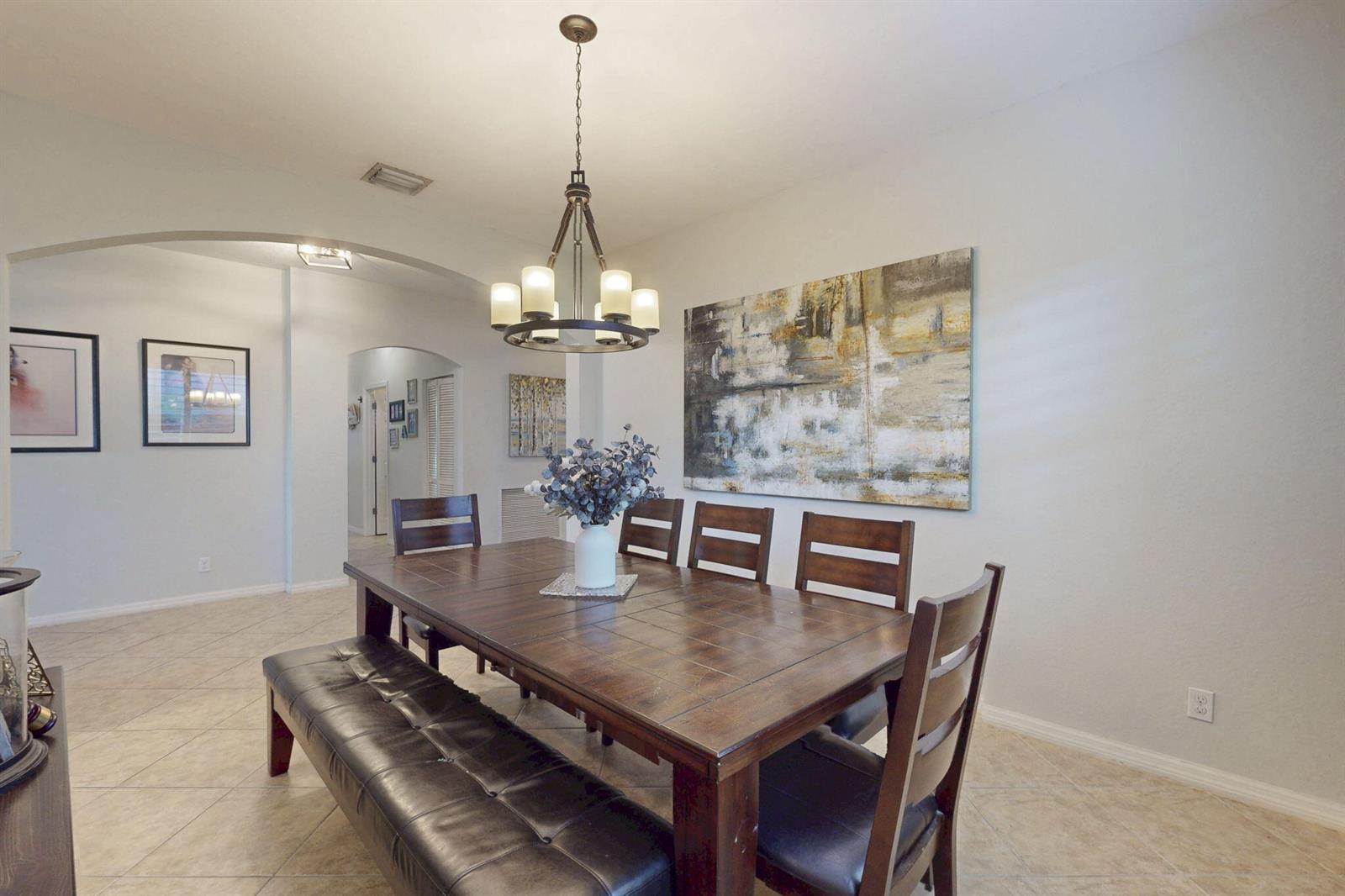 A dining room features a wooden table with chairs and a bench under a chandelier — 10551 Long Leaf Lane, Wellington FL 33414, WELLINGTON, FL