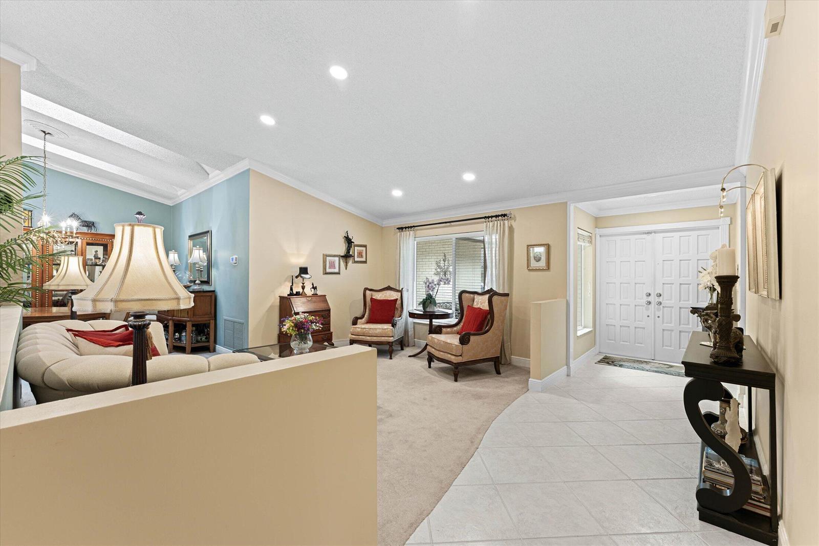 A living room with beige walls, carpeted flooring, and a tiled entryway near the front door — 2699 NW 38th Street, Boca Raton FL 33434, BOCA RATON, FL
