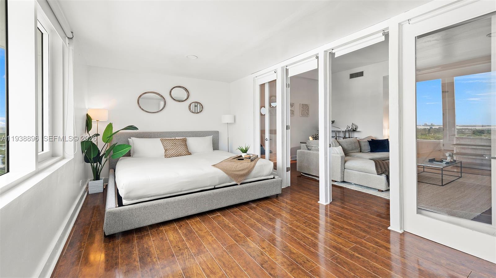 A bedroom with a gray platform bed, hardwood floors, and glass doors leading outside — 2301 Collins Ave # 1632, Miami Beach FL 33139, MIAMI BEACH, FL