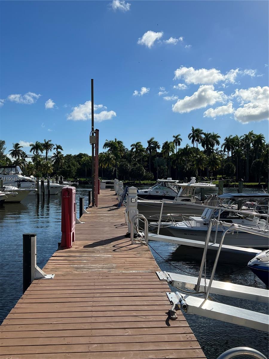 A wooden boat dock extends into a canal lined with moored boats and palm trees — 1700 NW North River Dr. #51, Miami FL 33125, MIAMI, FL