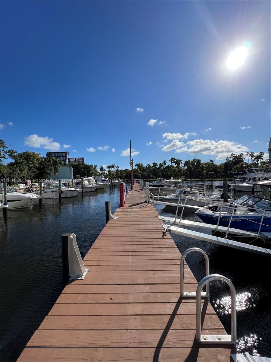 A wooden boat dock extends into a canal lined with moored boats and palm trees — 1700 NW North River Dr. #51, Miami FL 33125, MIAMI, FL