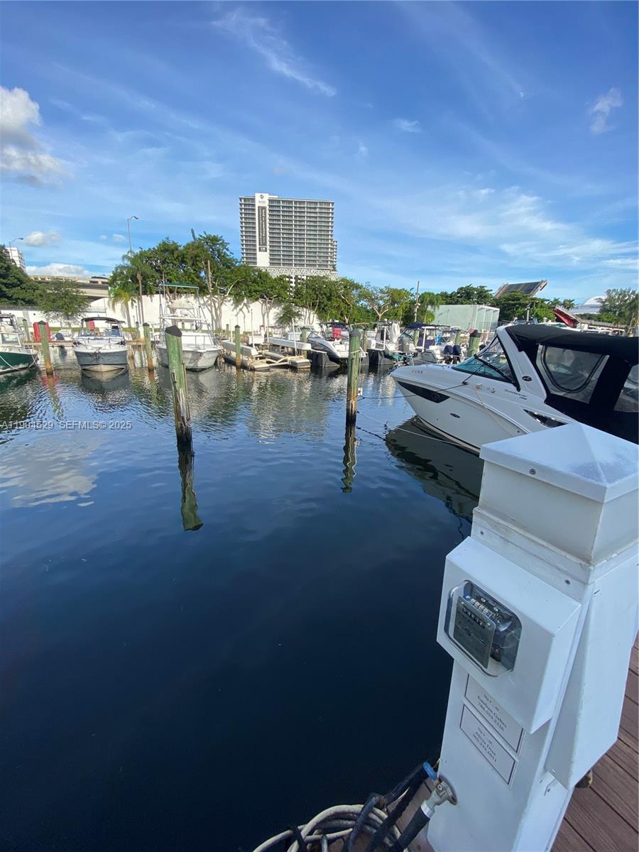 A view of a marina with several docked boats and a tall building in the background — 1700 NW North River Dr. #51, Miami FL 33125, MIAMI, FL