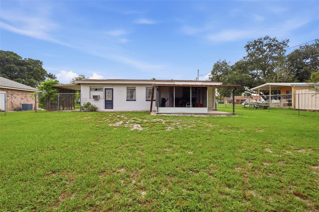 The exterior of a single-story house with a screened-in porch and a fenced backyard — 1119 MAYFLOWER AVENUE, DELTONA, FL