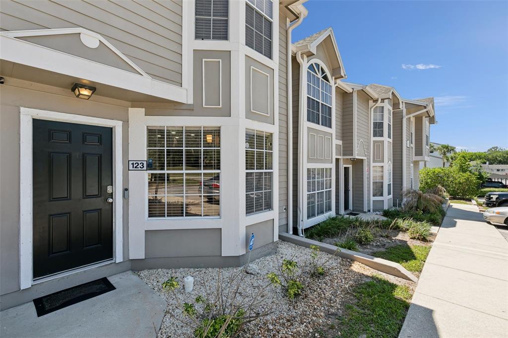 A tan multi-story townhouse exterior features a black front door and a bay window — 505 SUN RIDGE PLACE UNIT 123, ALTAMONTE SPRINGS, FL