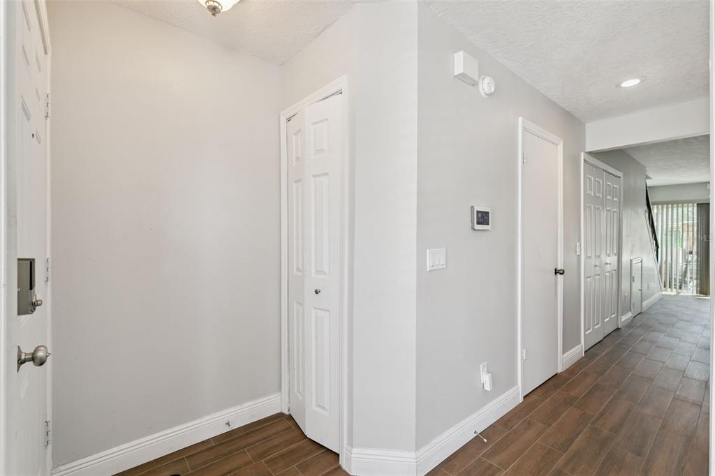 An entryway with wood-look tile flooring, white walls, and several white interior doors — 505 SUN RIDGE PLACE UNIT 123, ALTAMONTE SPRINGS, FL