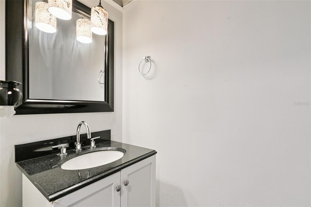 A bathroom features a white vanity with a black granite countertop and a framed mirror — 505 SUN RIDGE PLACE UNIT 123, ALTAMONTE SPRINGS, FL