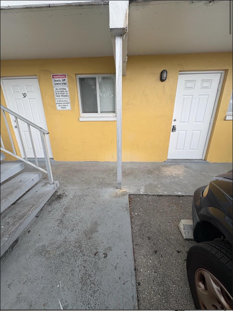 Exterior view of two motel room doors with a yellow wall and a support pillar — 1501 Crescent Circle # E39, Lake Park FL 33403, LAKE PARK, FL