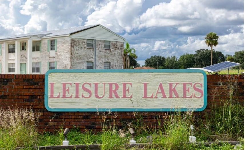A brick wall features a sign reading Leisure Lakes in front of a multi-story building — 3218 GOSSAMER AVENUE, LAKE PLACID, FL
