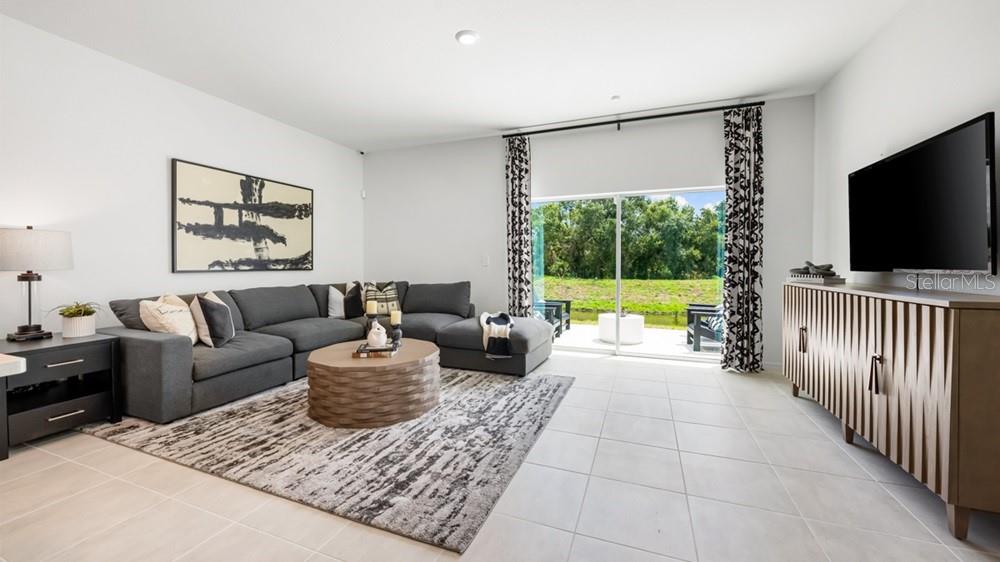 A living room features a gray sectional, patterned area rug, and sliding doors to a patio — 10810 ECLIPSE STREET, SARASOTA, FL