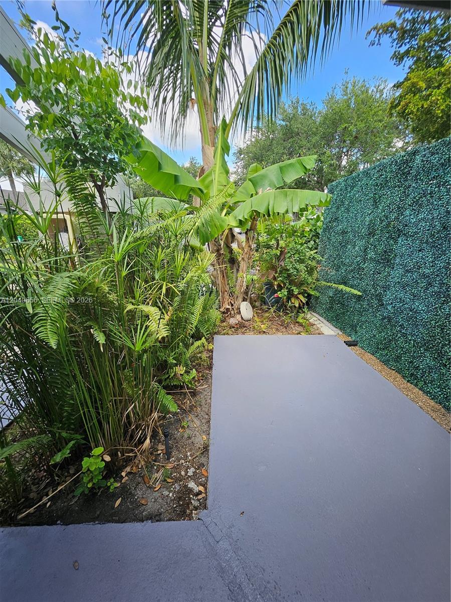 A small gray patio sits beside a lush garden with a palm tree and greenery — 3015 SW 21st Ter # 371B, Delray Beach FL 33445, DELRAY BEACH, FL