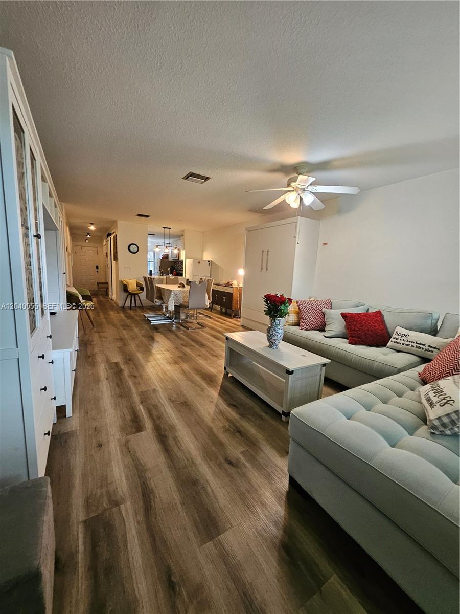 A living room with light wood-look flooring, a sectional sofa, and an open dining area — 3015 SW 21st Ter # 371B, Delray Beach FL 33445, DELRAY BEACH, FL