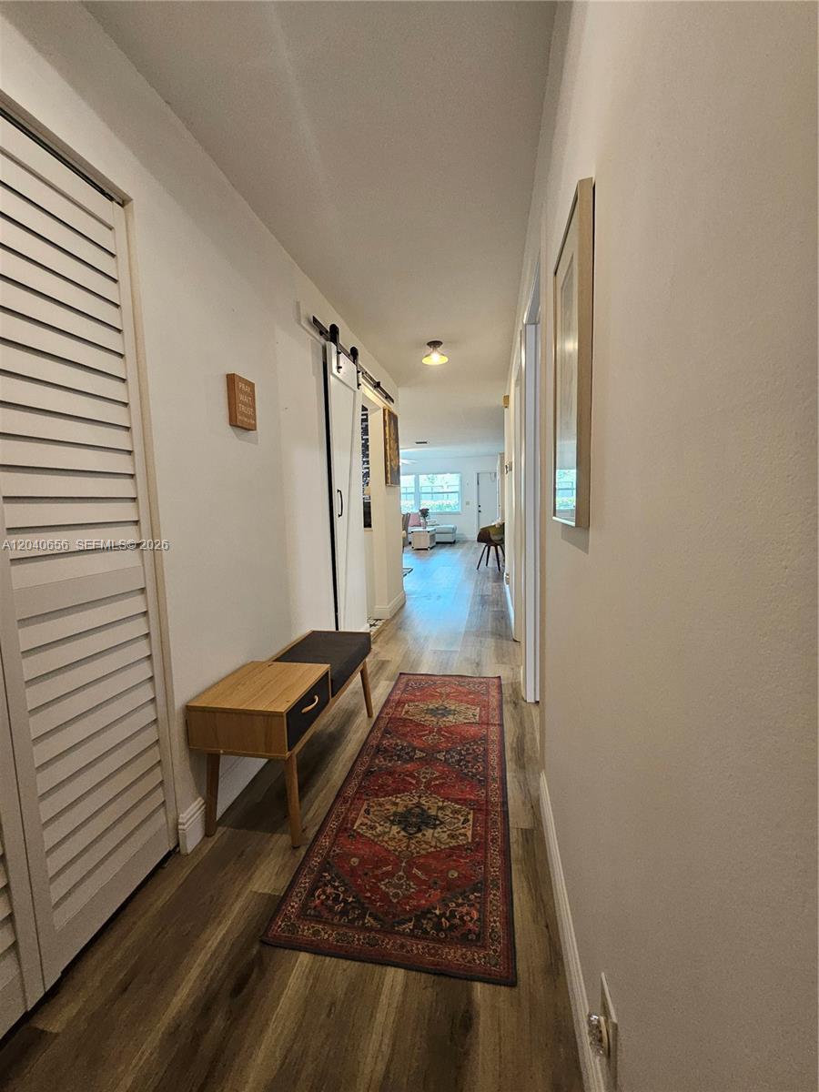 A hallway with wood-look flooring, a bench, a runner rug, and a sliding barn door — 3015 SW 21st Ter # 371B, Delray Beach FL 33445, DELRAY BEACH, FL