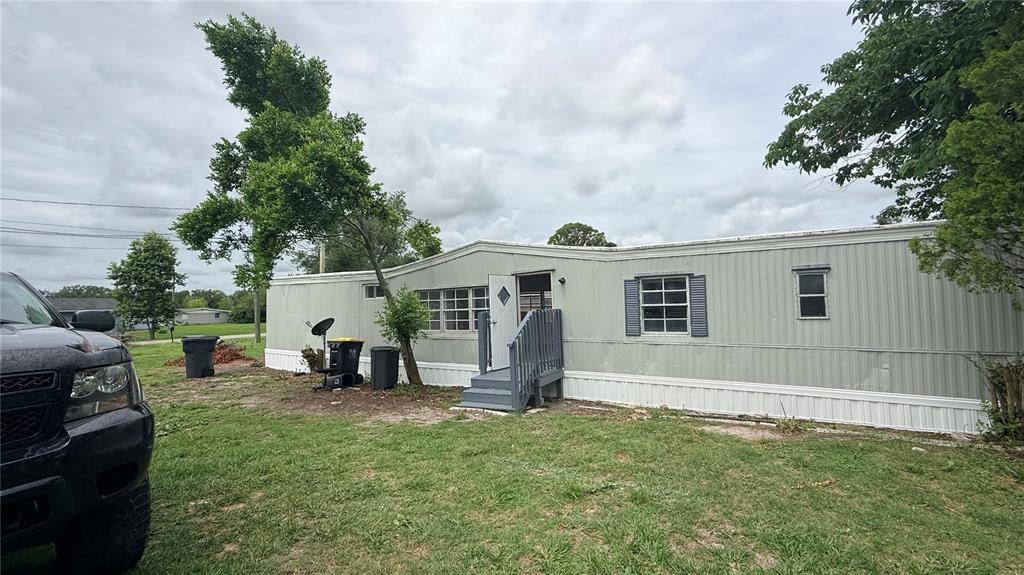 A light green mobile home with a small wooden staircase leading to the front door — 115 WHITFIELD STREET, MULBERRY, FL
