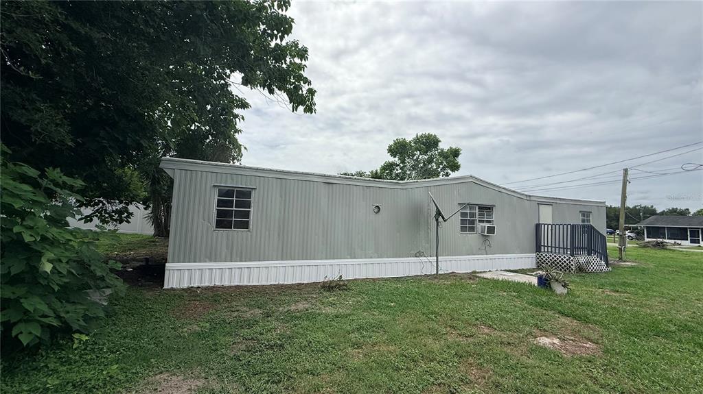 A single-story mobile home with gray metal siding sits on a grassy lot — 115 WHITFIELD STREET, MULBERRY, FL